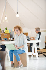 Obraz premium Woman using laptop and smiling in office
