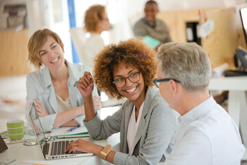 Fototapeta premium Three office workers talking at desk with laptop
