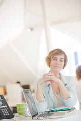 Portrait of woman sitting at desk with laptop in office