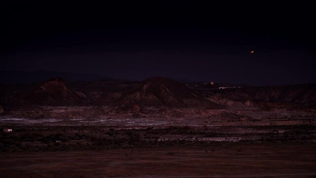 Time lapse of night is falling over Tabernas desert landscape in Almeria, Spain. Full moon on sky. Movie location set for spaghetti western.