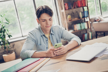 Portrait of attractive focused guy learner practicing using gadget searching information at loft industrial interior indoors