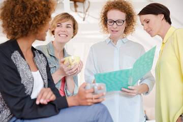Women with coffe cup talking in office