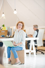 Obraz premium Woman using laptop and smiling in office