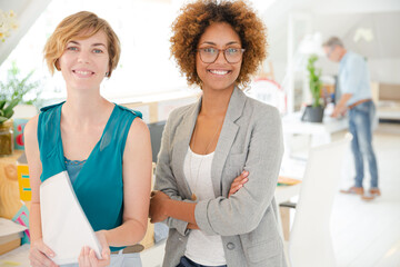 Women  smiling in office, holding documents