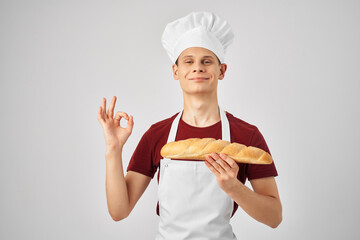 a man chef in a white apron holds a loaf in his hands Baker