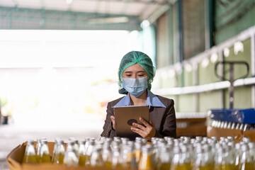 Asian female specialist worker wearing hairnet and protective mask working and checking goods or...