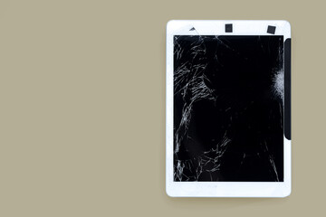 cracked or broken screen of smartphone or tablet temporarily fixed with black tape on beige pastel background, isolated object with clipping path