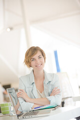 Portrait of woman sitting at desk with laptop in office