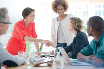 Office workers shaking hands at desk