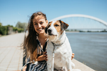 Beautiful young woman enjoying outdoors with her adorable adopted mixed breed dog. Bright sunny day.