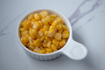 Corn boiled in a white ceramic cup on a white background.