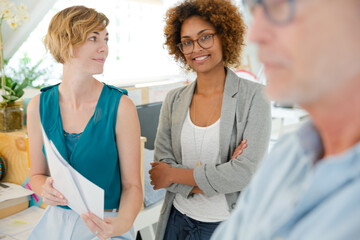 Obraz premium Colleagues talking and smiling in office, holding documents