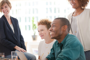 Fototapeta premium Office workers talking and smiling at desk
