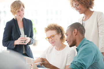 Office workers talking and smiling at meeting