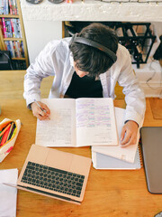 Teenage boy with headphones doing homework at table