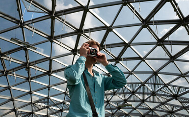 A young man with a photo camera taking pictures of landmarks.