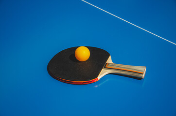 Ping pong racket and ball on a blue tennis table