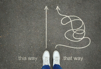 Legs in white sneakers in front of straight and tangled arrows leading to the same goal on the gray...