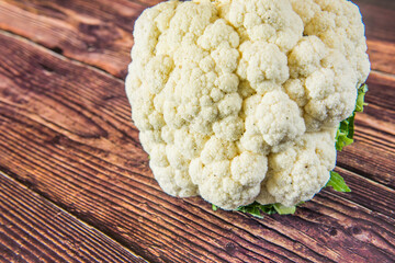 Fresh white bio cauliflower with green leaves on wooden table from farb village gardening