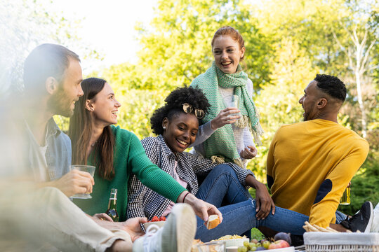 Smiling young friends sitting together in public park