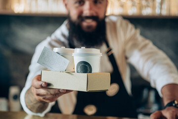 An Anonymous Barista Serving Two Take Away Paper Cup with Espresso to You.

Smiling waiter giving...