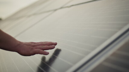 Close up of a young engineer hand is checking the operation of sun and cleanliness of photovoltaic solar panels on a sunset. Concept.renewable energy, technology, electricity, service, green, future.
