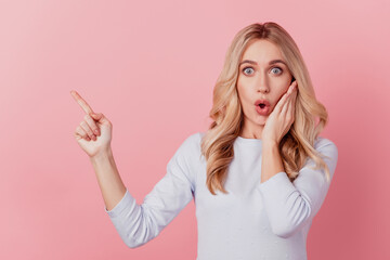 Portrait of dreamy adorable lady point finger empty space open mouth hand cheek on pink background