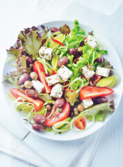 Healthy salad with feta cheese, various olives, leek and tomatoes. White wooden background. Top view. Close up. 	