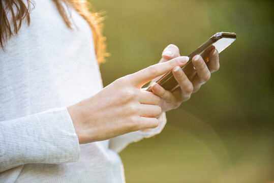 Mid section of young woman using smartphone in park