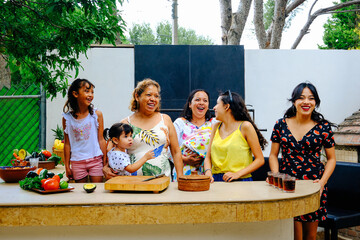 Cheerful multi-generational family preparing salsa at kitchen counter in backyard