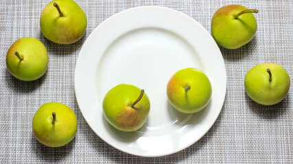 Ripe green pears on a plate on the table.