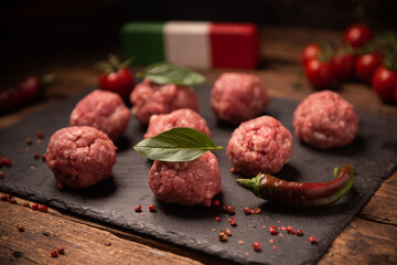Raw meatballs on  dark basalt plate