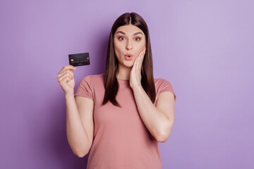 Photo of attractive young girl amazed shocke hand touch cheek holding credit card isolated violet color background