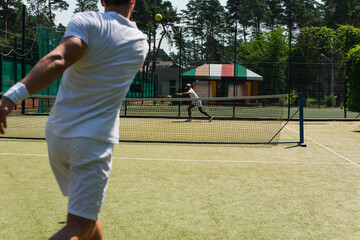 African american man playing tennis with blurred friend outdoors