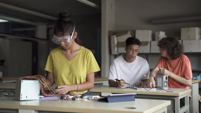 Asian teenage female Student wearing protective goggles working on electronics circuit board in the science technology workshop - Digital Innovation in High School Education