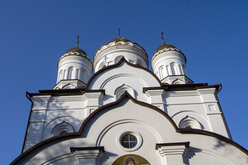 Fototapeta premium Gilded domes and white walls of a Christian church against a cloudless sky