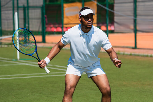 Focused african american sportsman playing tennis on court - Powered by Adobe