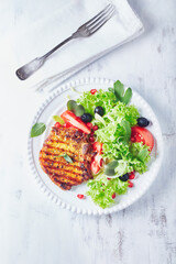 Grilled pork steak with fresh salad. White wooden background. Top view. copy space. 