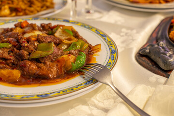 Plate of beef with peppers, vegetables and hot sauce served in a Chinese restaurant with tablecloths and forks