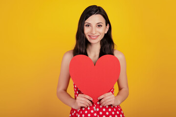Obraz na płótnie Canvas Portrait of adorable lady hold heart figure valentine day wear dotted red dress on yellow background