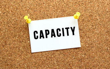 CAPACITY is written on a card attached to the corkboard with a button. Reminder on the office board.