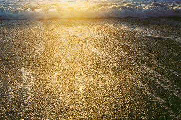 sunset on the beach. Golden hour reflect light of gold on the sand and the water.