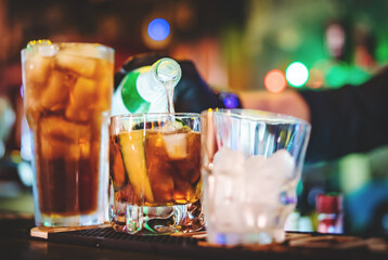 hands of a bartender with black gloves making cocktail on a bar counter.
