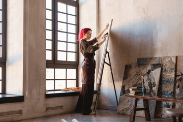 Young woman artist painting in studio
