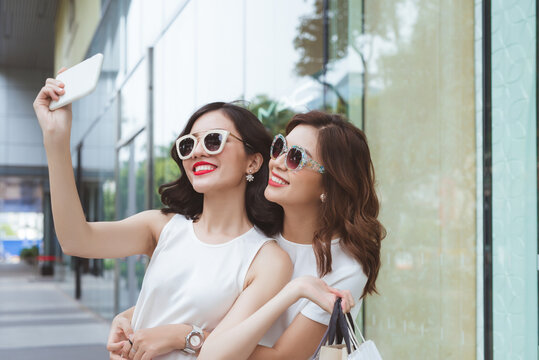Young girls walking in shopping center and make selfie photo together