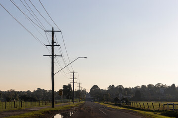 Road with electric poles on clear sky.