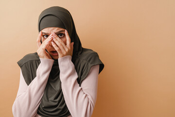 Young muslim woman in headscarf covering her face