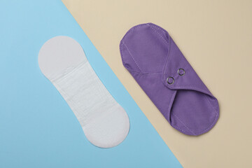 Pantyliner and reusable menstrual pad on color background, flat lay