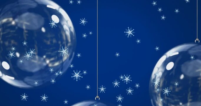 Animation of snow falling over christmas bauble decorations on blue background