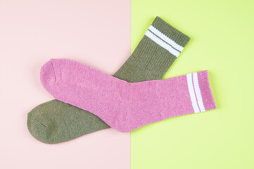 Two socks green and pink on a pastel multi-colored pink and green background with copy space, top view